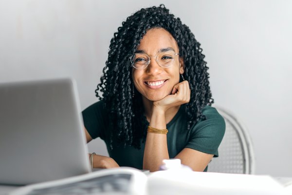 Photo of smiling woman with curly hair, with a laptop