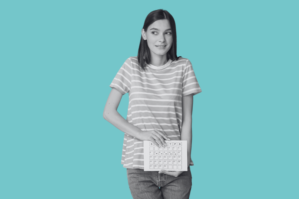 A teenager holding a menstrual calendar looking confused.