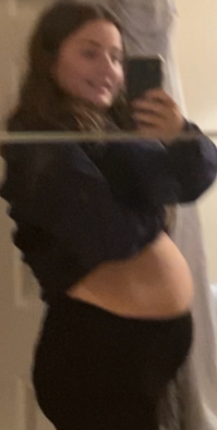 A young white women showing her bloated stomach