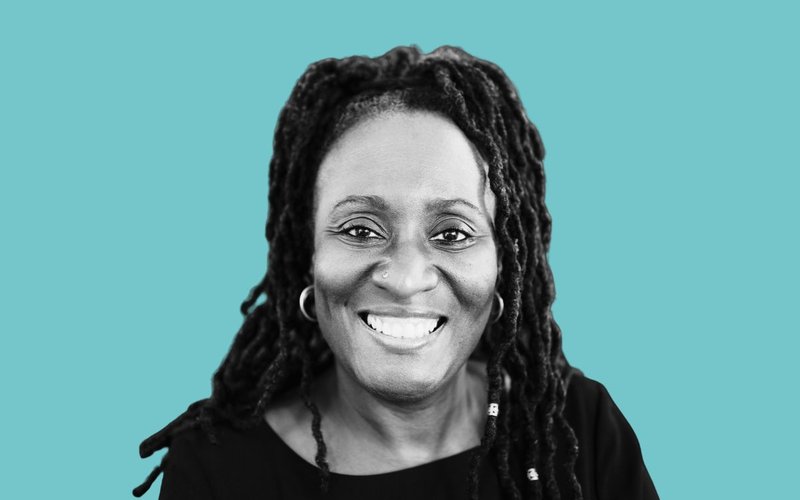 Middle aged woman smiles at camera black and white on blue background