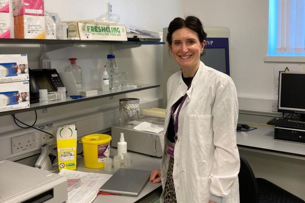 Dr Nicola Tempest smiling in her lab surrounded by research equipment
