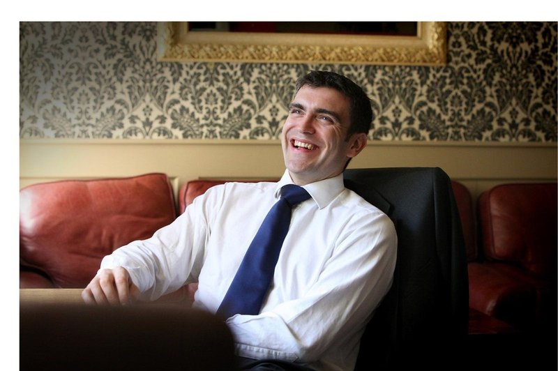 Dr Stephen Quinn smiling on a leather sofa