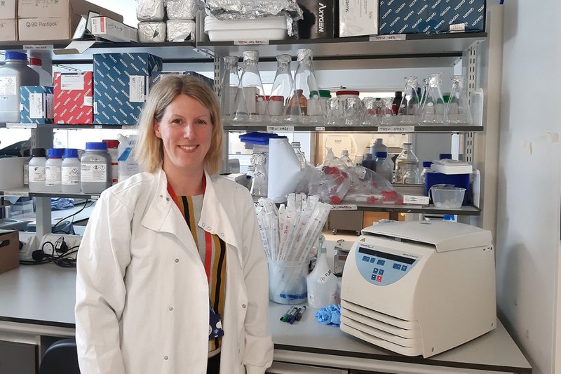 Dr Sarah Kitson in a white lab coat surrounded by lab equipment