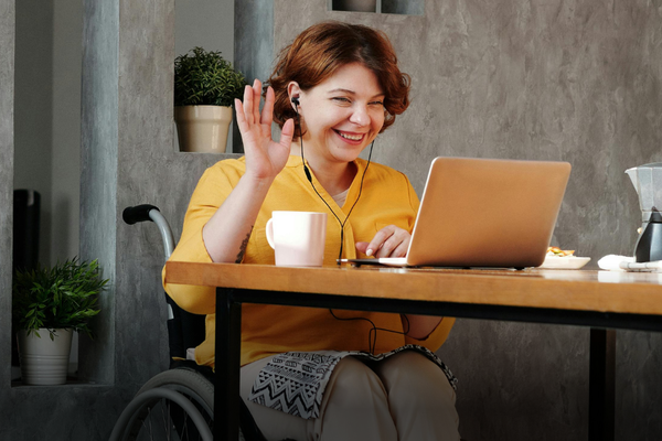 Woman does course on laptop, she is in a wheelchair and smiling