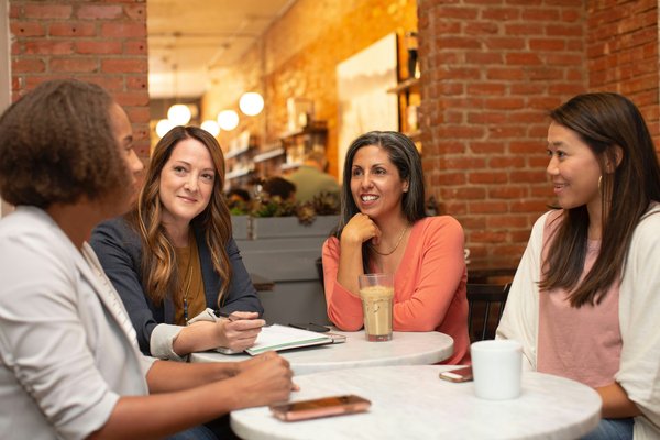 A group of women sitting around a table in a workplace setting a table i a