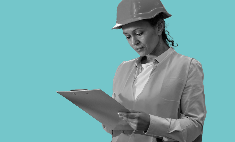 A women wearing a hard hat looking at a clipboard.