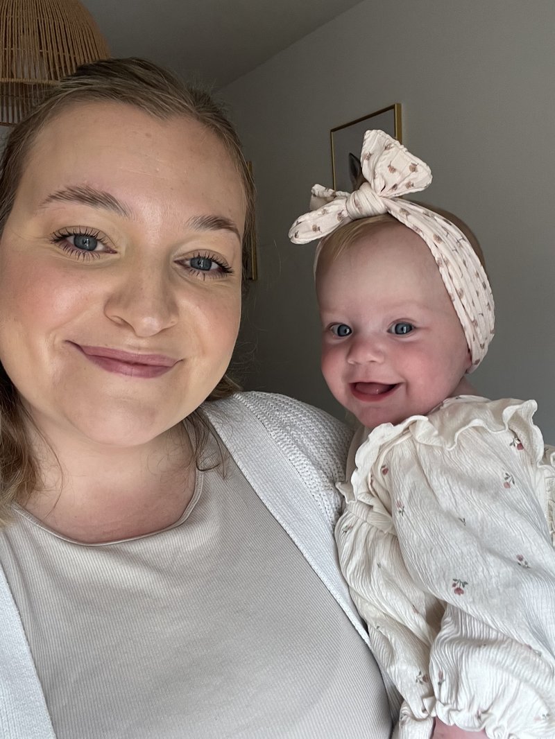 Photo of a white woman holding her baby, both are smiling