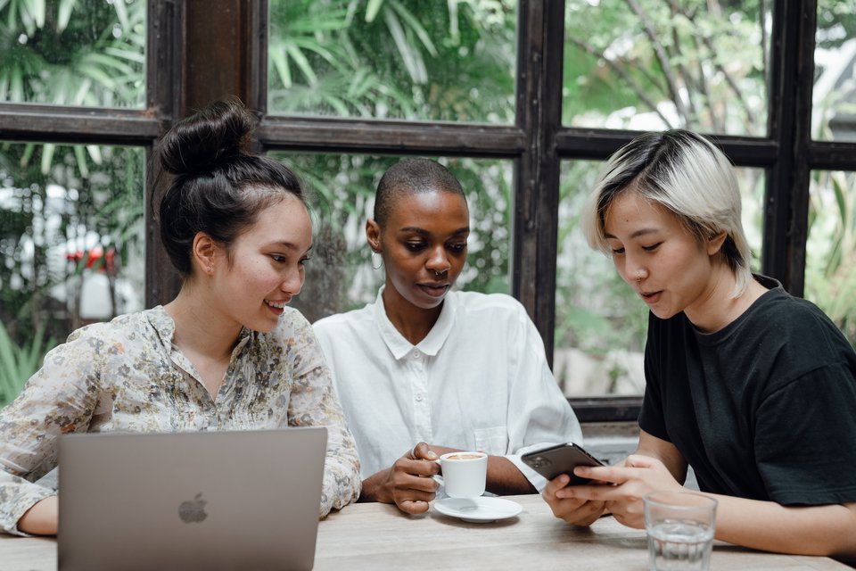 Three women sitting at a table looking at content online